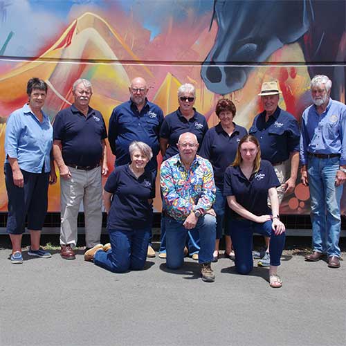 A group portrait of the RAS Foundation Community Futures Grant recipients standing before a colourful mural backdrop outdoors.