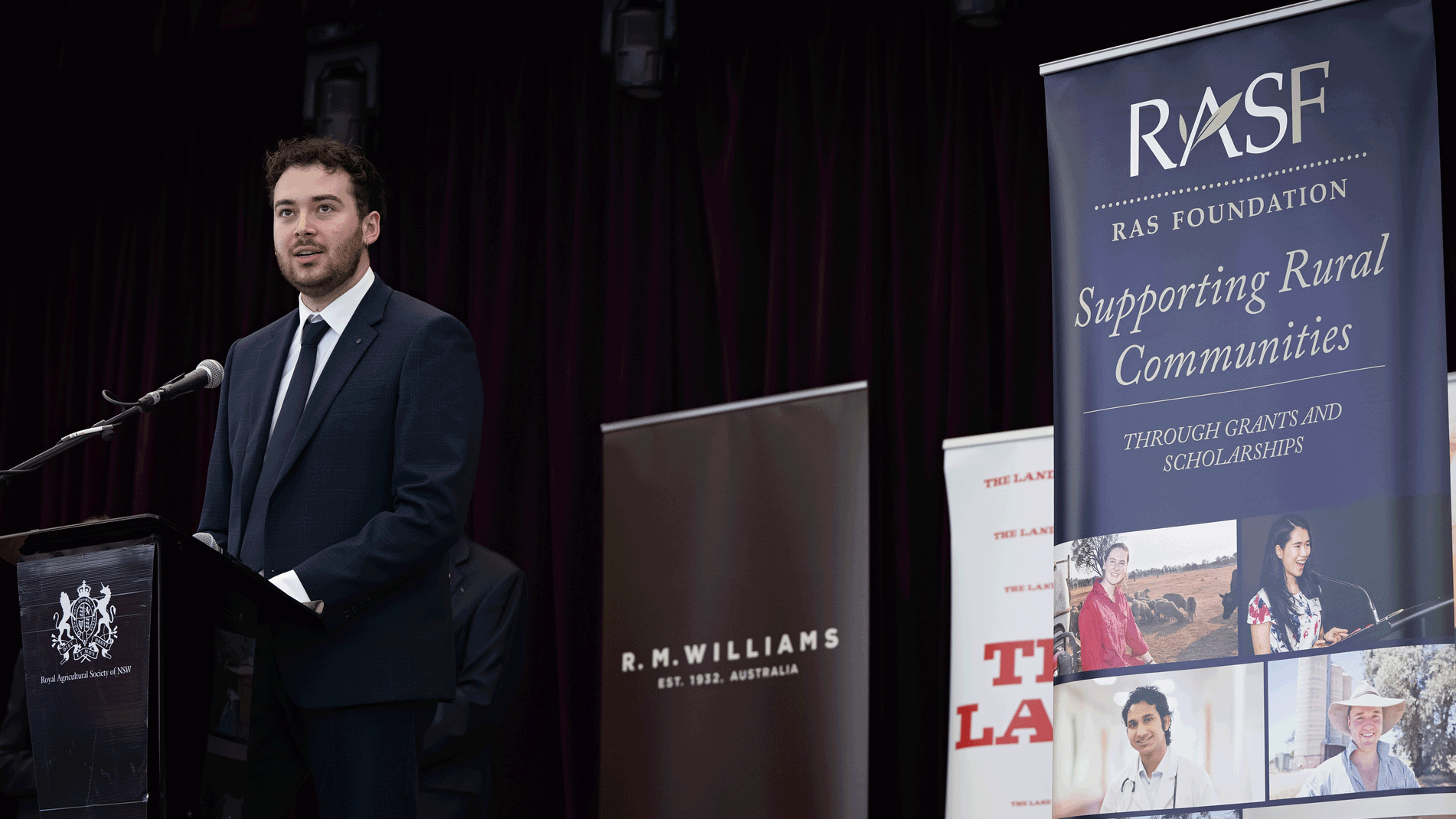 JB Fairfax Award 2025 winner Nick Newling in a dark suit, speaking at a podium in front of RAS Foundation banners.