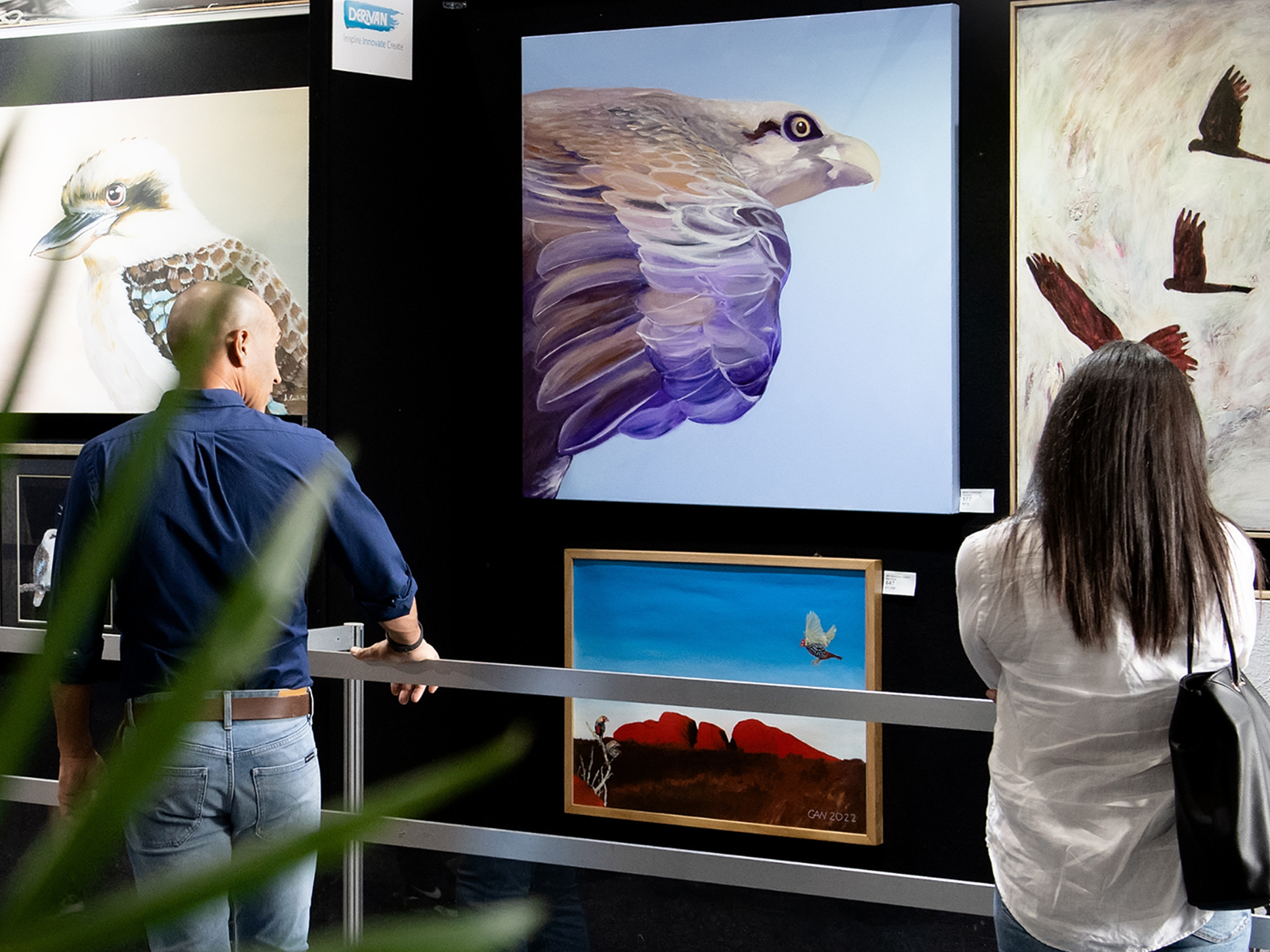 Visitors viewing bird-themed paintings on display at the Sydney Royal Arts & Crafts Competition.