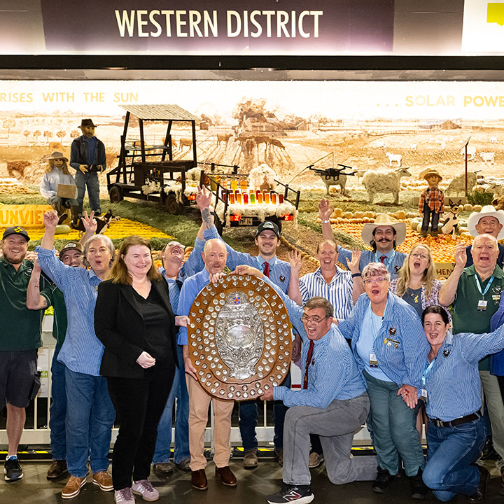 Western District Exhibitors holding large award shield in front of their produce display for the Sydney Royal District Exhibits.