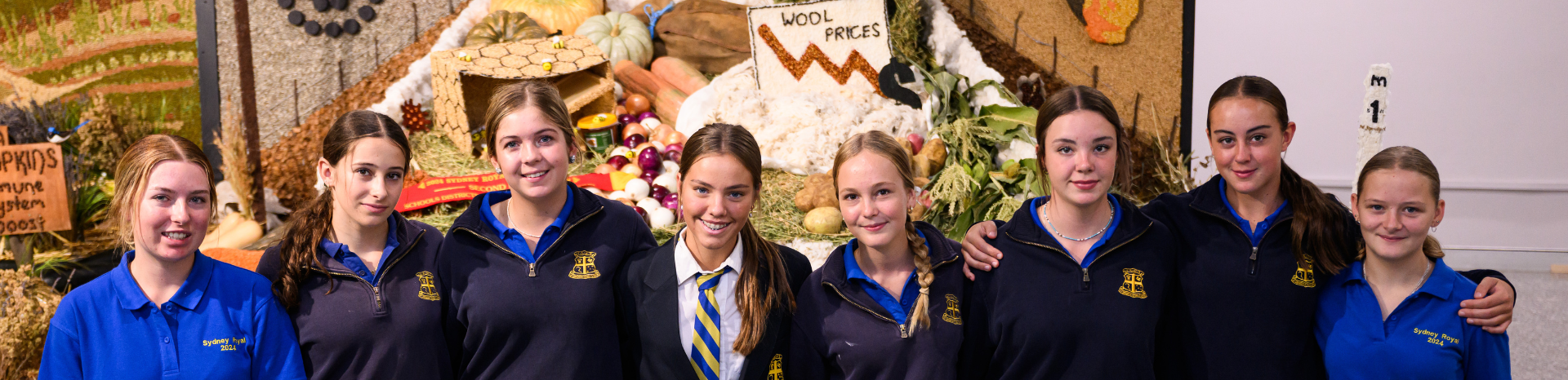 A group of students in blue uniforms pose in front of a produce display at the Sydney Royal Easter Show.