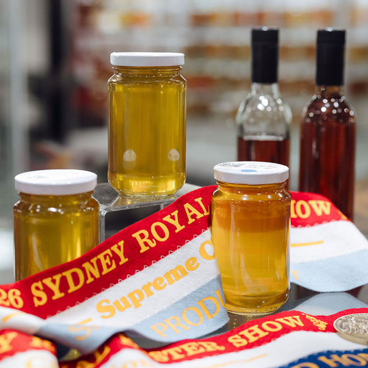 Jars of honey displayed with Sydney Royal award ribbons and medals at the Sydney Royal National Honey Show.