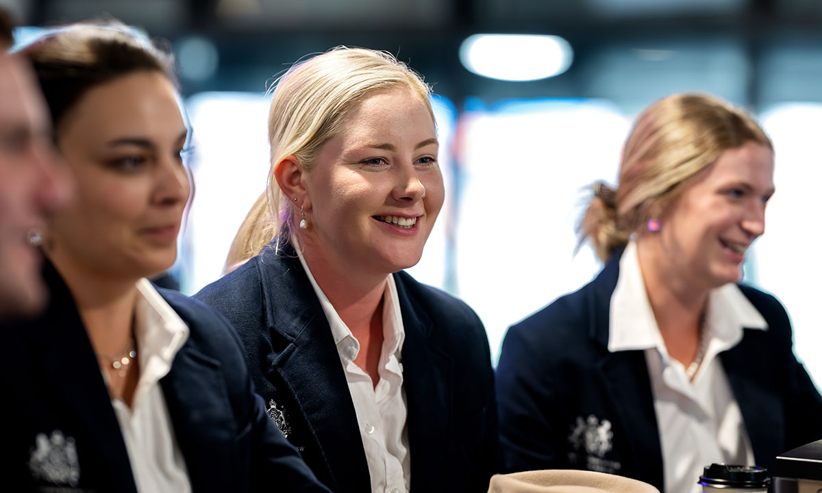 RAS Rural Achiever Award finalist Loretta Nicholas, a blong woman with pearl earrings, smiling with other finalists indoors.