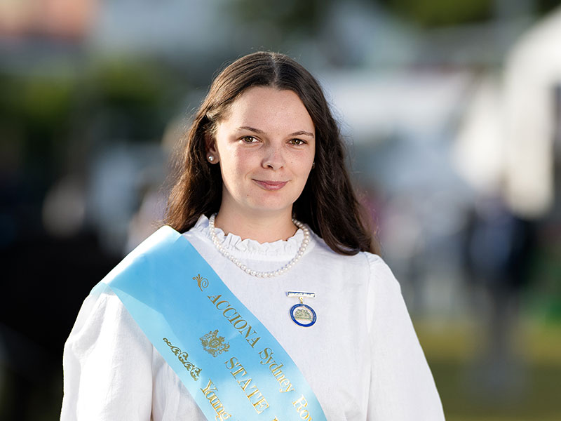Headshot of 2026 Young Woman finalist Taylee Jade Short, a young woman with long straight hair, wearing a white shirt sash and a light blue sash.