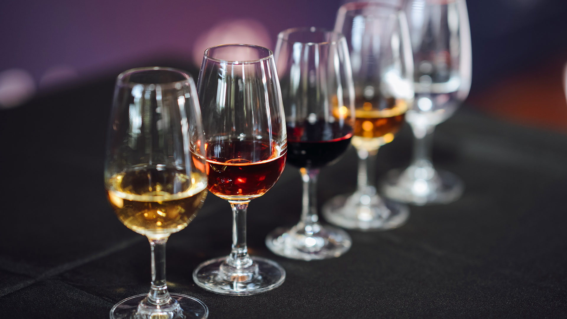 Five glasses filled with dark and amber-coloured distilled spirits, arranged on a judging table at the Sydney Royal Distilled Spirits Show.
